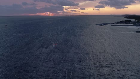 silueta de un hombre en una tabla de cometas en el mar al atardecer, vista aérea
