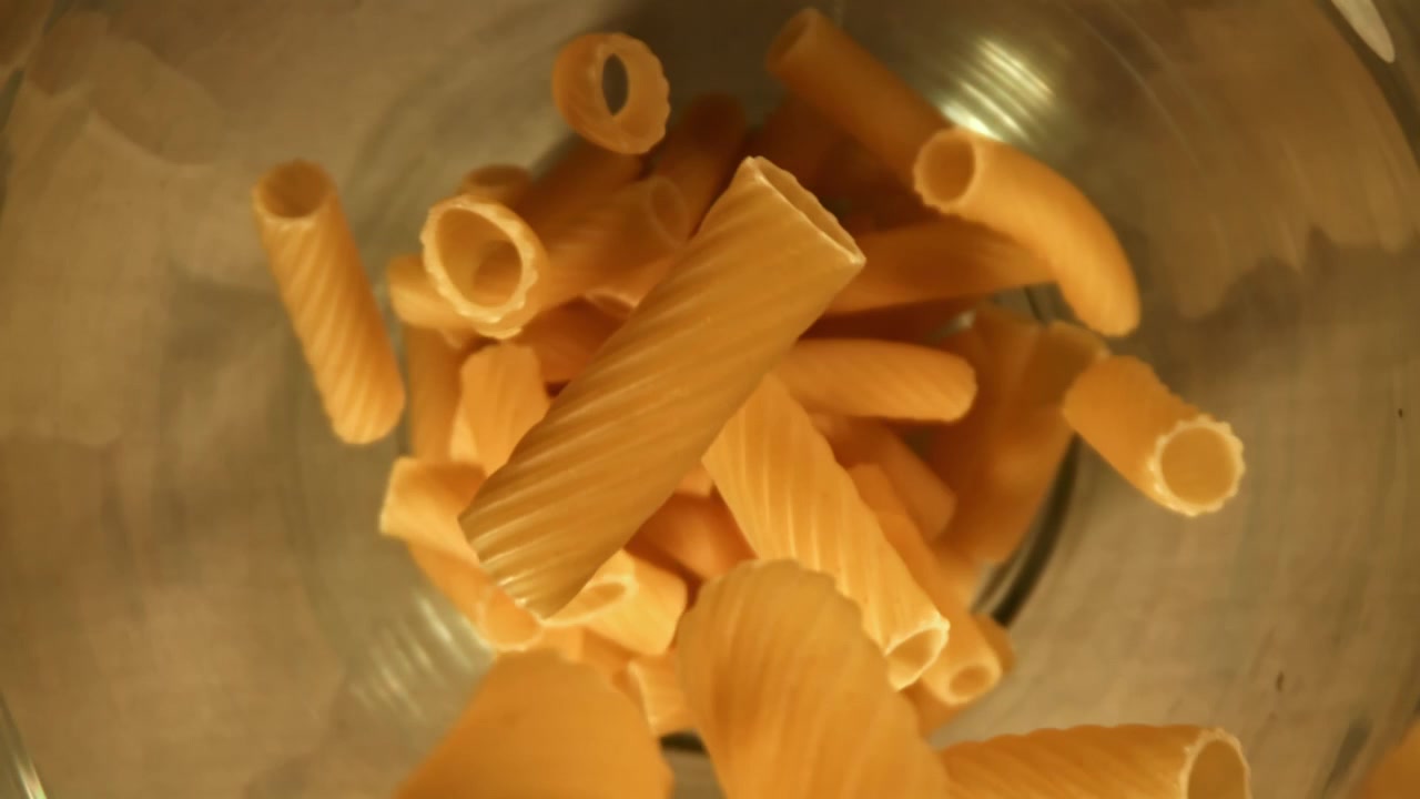 Pasta secca che cade in una ciotola di vetro al rallentatore