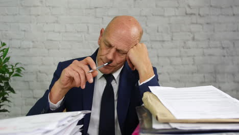 hombre de negocios aburrido con montones de papeleo en su escritorio