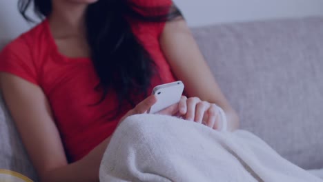 집의 소파에서 스마트폰을 사용하는 아시아 여성에 대해 떠다니는 쇼핑 카트 아이콘
