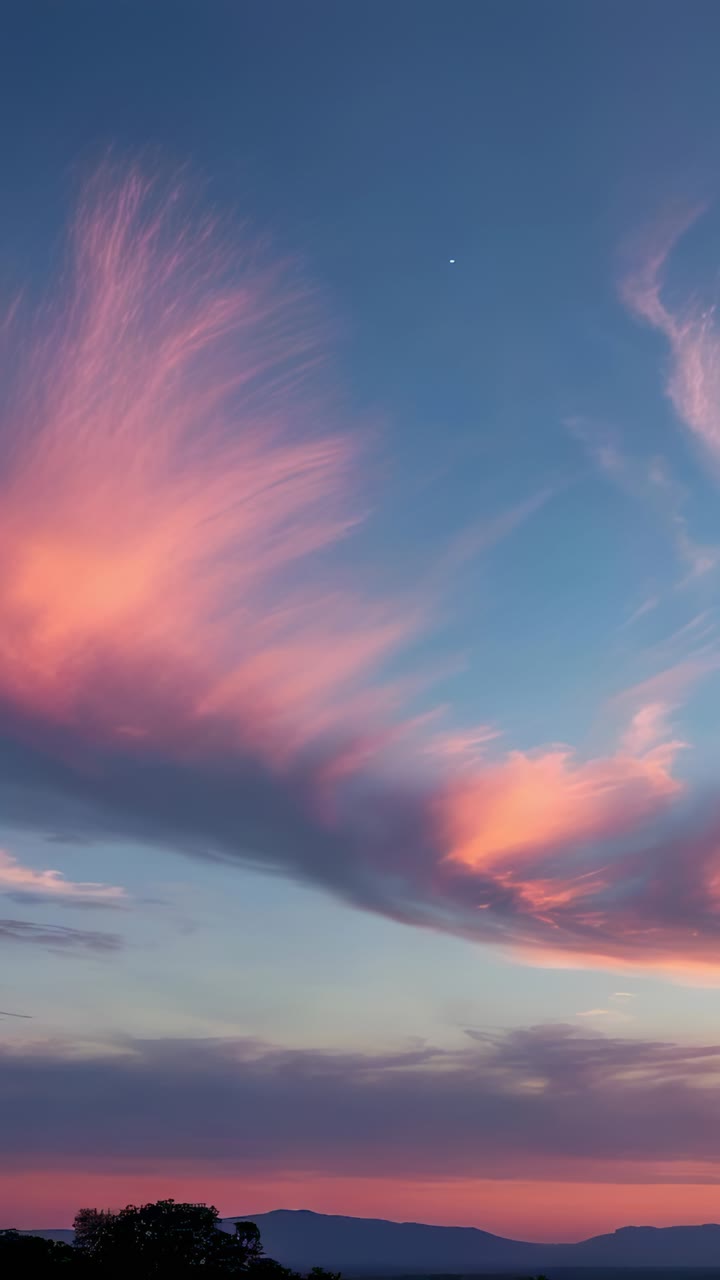 Vertical video: Pink clouds shifting above ridge while sun dipping below horizon, with planet