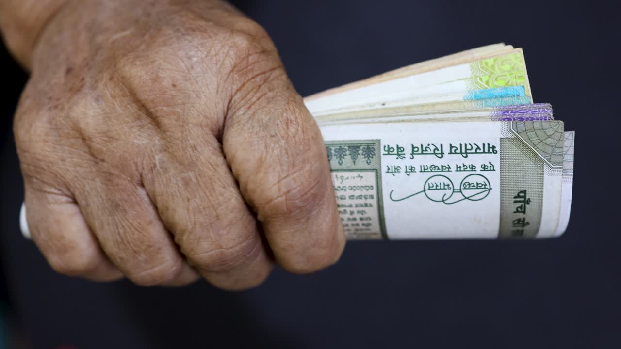 old age hand gripping cash bills from India concept of social security, investment and income