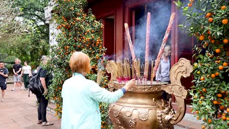 person lighting incense at temple in hanoi