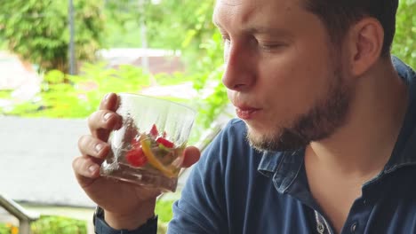 man enjoying a refreshing fruit cocktail outdoors