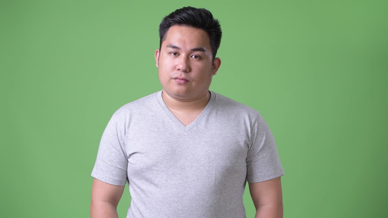 초록색 배경에 젊은 잘생긴 과체중 아시아인