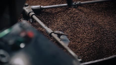 coffee roasting process - coffee beans in large roasting machine and machine detail.