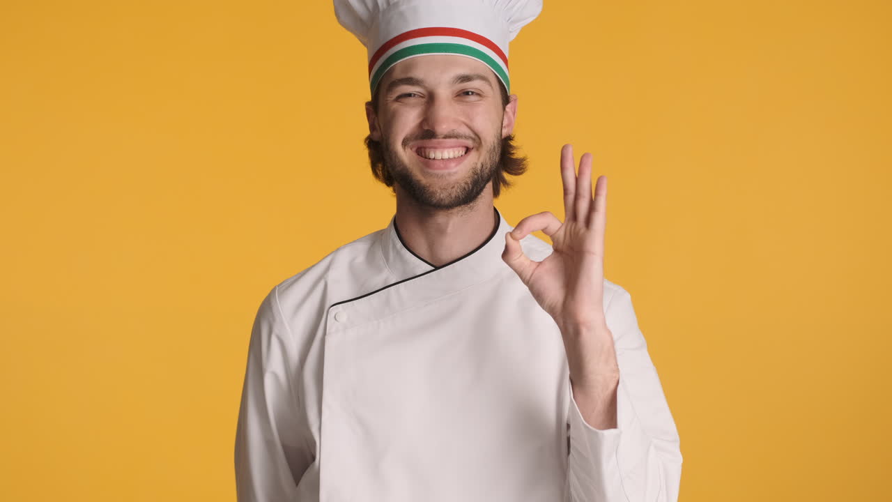 chef caucásico frente a la cámara sobre un fondo amarillo.