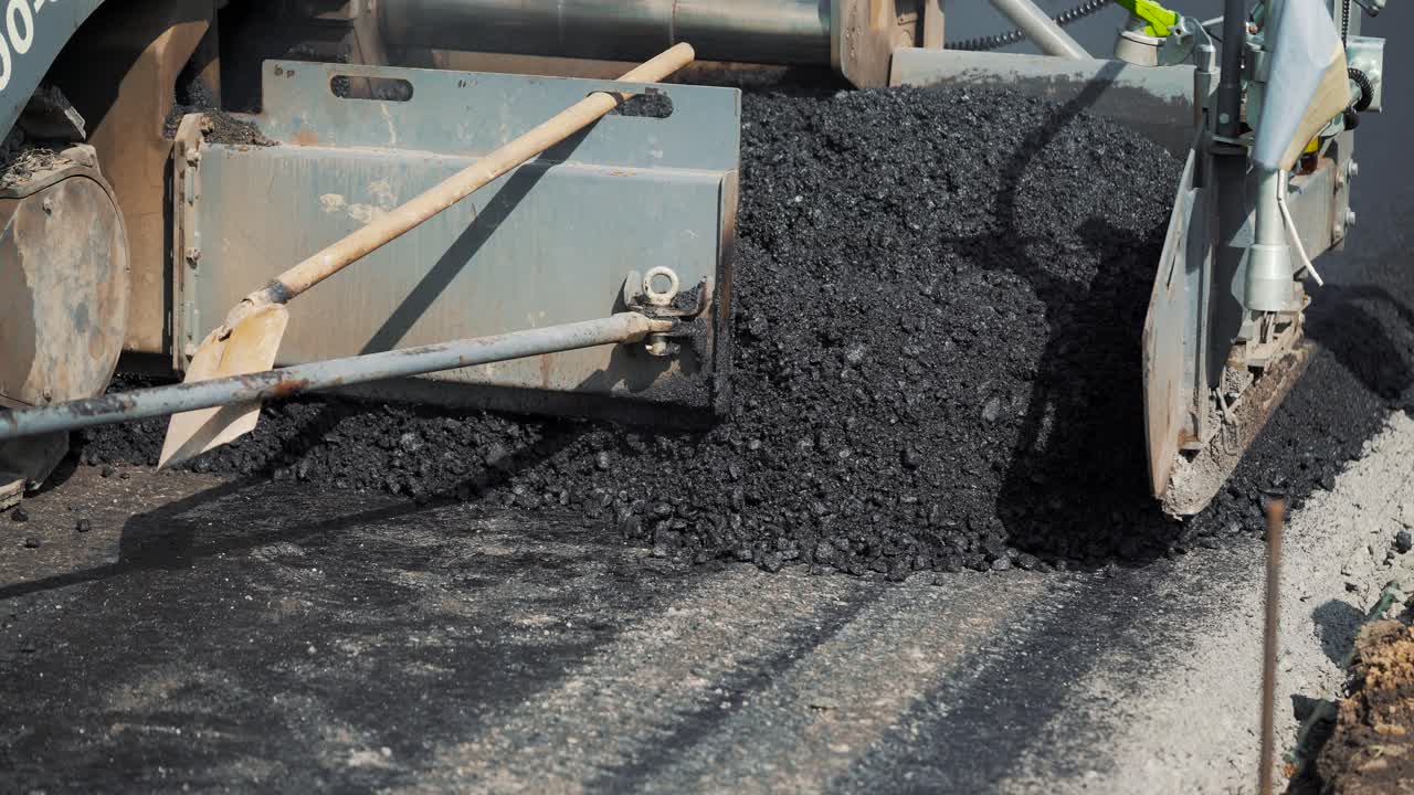 professional equipment is filling with bitumen and smoothing it on the road for packing asphalt. Modern road repair technology