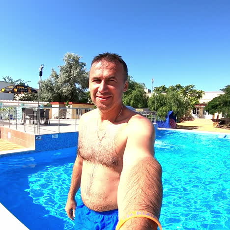 man is falling into the water outdoors in summer. swimming pool background and a man holding camera and fall back into water. summer vacation.