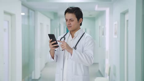 angry indian doctor scrolling through phone