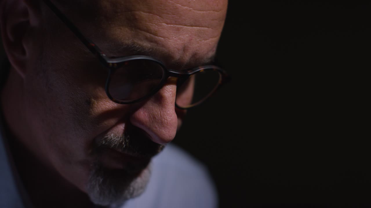 Close Up Of Depressed Mature Man Struggling With Mental Health Sitting In Darkness In Real Time With Low Key Lighting 8