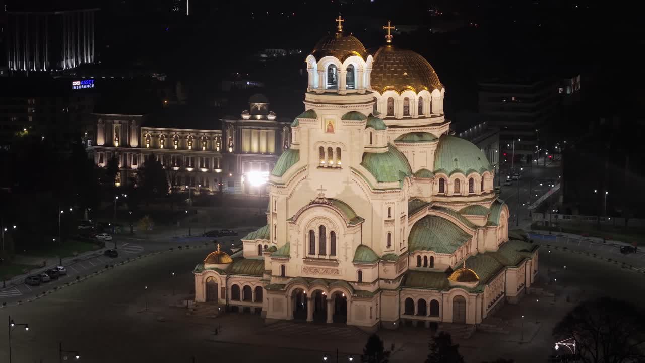 A drone orbit captures the majestic illuminated Alexander Nevsky Cathedral glowing against the night sky, revealing its golden domes and dominating presence in Sofia’s city center