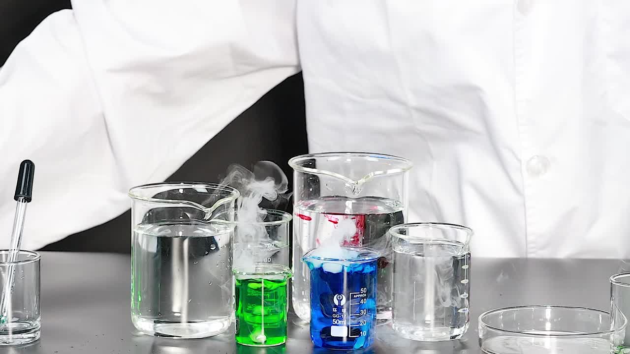 Uno scienziato in camice da laboratorio bianco aggiunge un liquido rosso a dei becher creando fumo