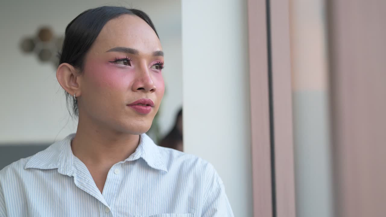 Thai transgender person in coffee shop smiling and thinking close-up portrait