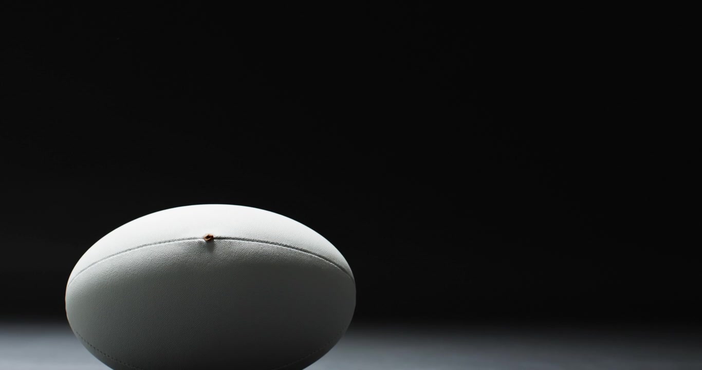 White rugby ball on black background with copy space, slow motion