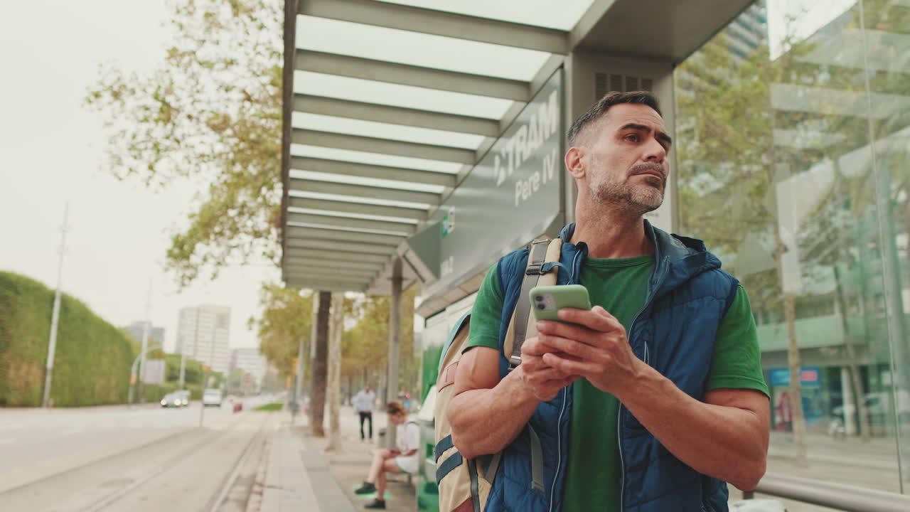 hombre usando un teléfono inteligente en una parada de autobús
