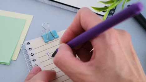 to do list - hand writing a note with a black marker in a spiral notebook, overhead view.