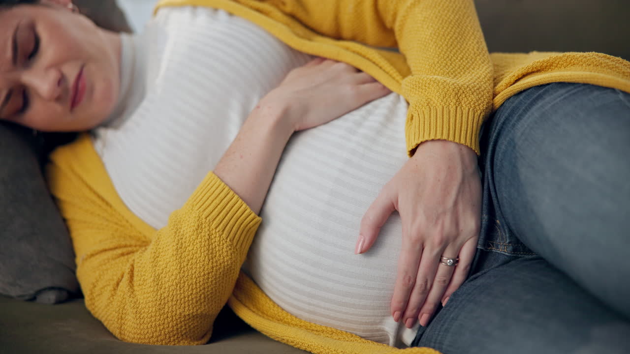 Pregnant woman lying on sofa at home
