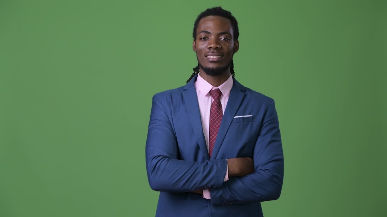joven empresario africano guapo con dreadlocks contra un fondo verde