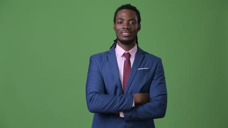 young handsome african businessman with dreadlocks against green background