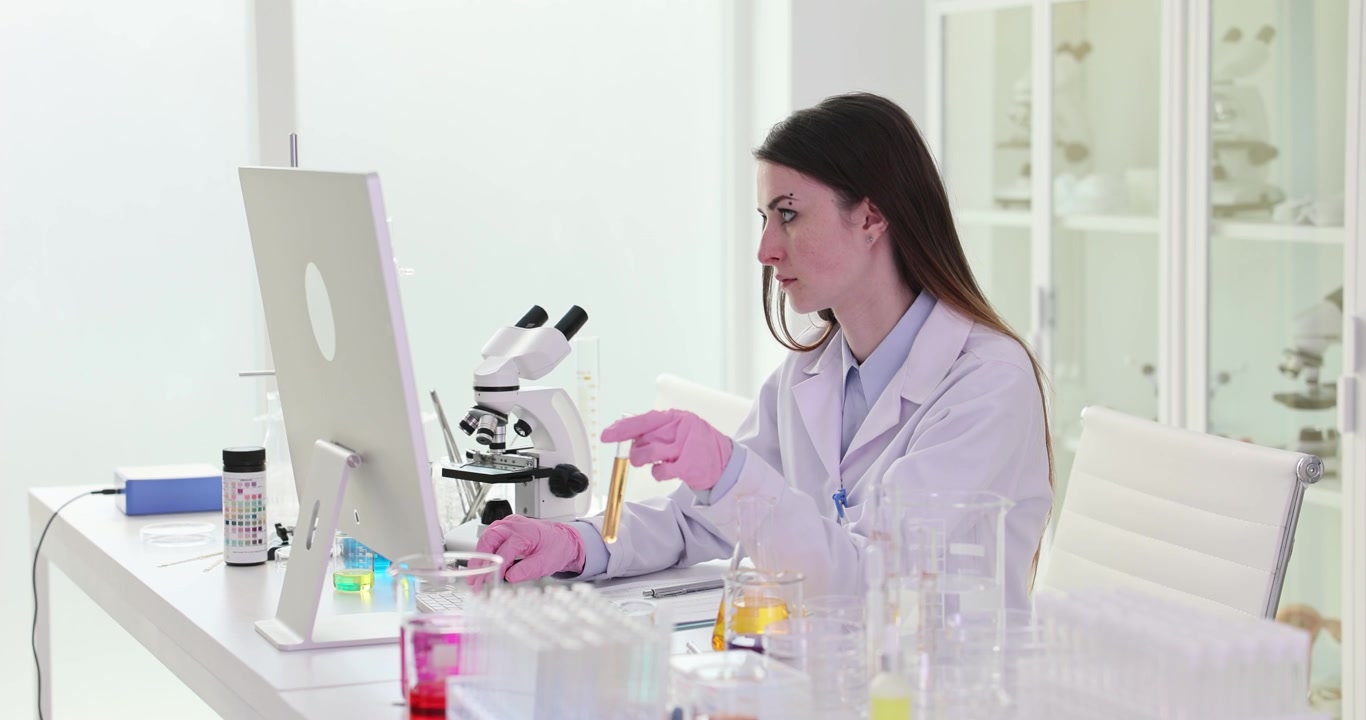 Scienziata esamina un campione liquido digitando al computer