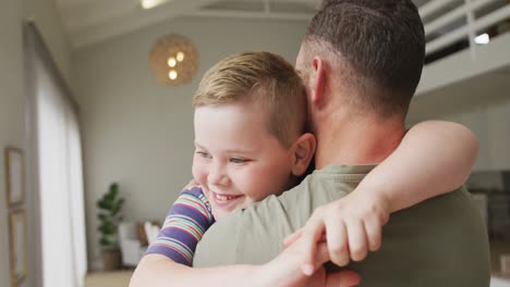 Kaukasischer-Junge-Umarmt-Seinen-Vater-Im-Wohnzimmer-Zu-Hause