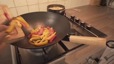 dropping cut bell peppers into hot pan with cooking oil