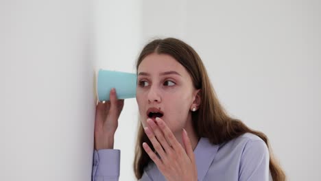 Young Woman Eavesdropping Through Wall with a Cup