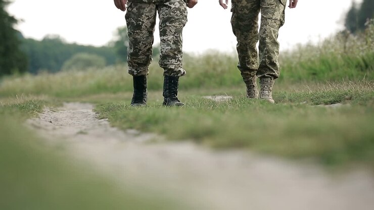 Primo piano delle gambe di un soldato. Primo piano delle gambe di un soldato con vecchi stivali da combattimento da paracadutista dell'esercito.