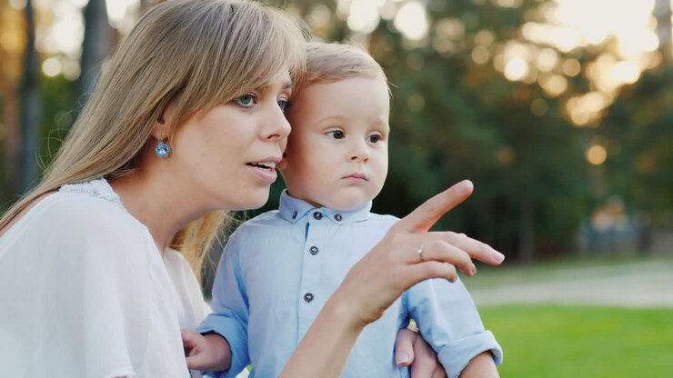 Eine junge Mutter spaziert mit ihrem Baby-Sohn im Park. Mama zeigt dem Kind etwas Interessantes 4K Zeitlupe
