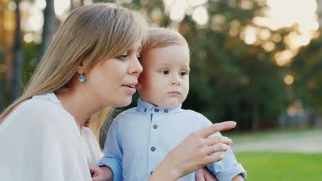 a young mother with her baby son walks in the park mom shows the child something interesting 4k slow