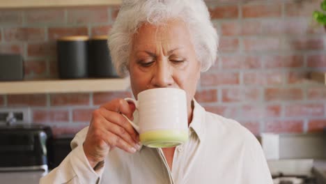 Senior-mixed-race-woman-drinking-a-beverage-at-home