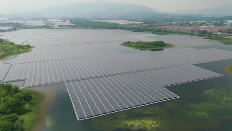 Aerial view of a large floating solar power plant installed on Serendah Lake in Sungai Rawang, Malaysia, with rows of solar panels stretching across the water, surrounded by greenery