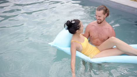 a young biracial couple enjoys time in a pool, copy space