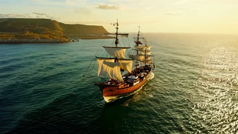 a tall ship sailing at sunset