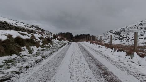 Driving-snowy-rural-country-road-in-slippery-winter-cold-weather-conditions-on-frosty-morning