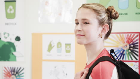in school, young girl smiling with backpack surrounded by colorful educational posters