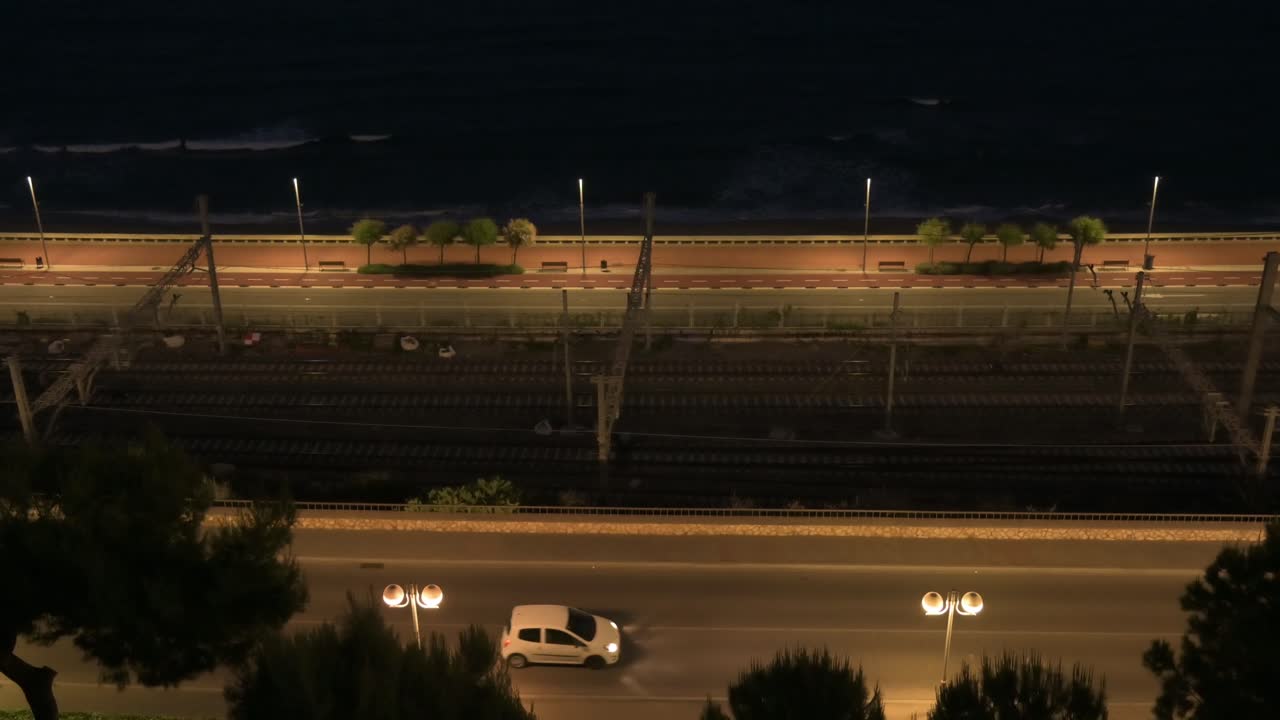 Night view of Tarragona seafront with traffic, railway tracks and city lights