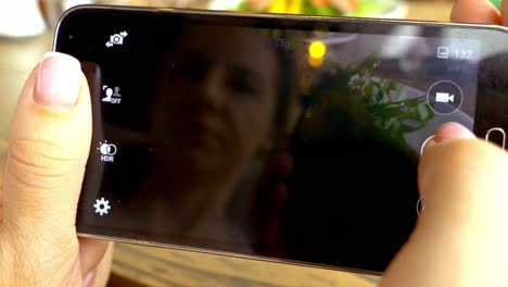 woman taking photo of food with smartphone at restaurant
