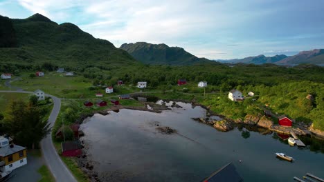 close up flyover of a small village with red and white houses on the mountainous coast of northern norway