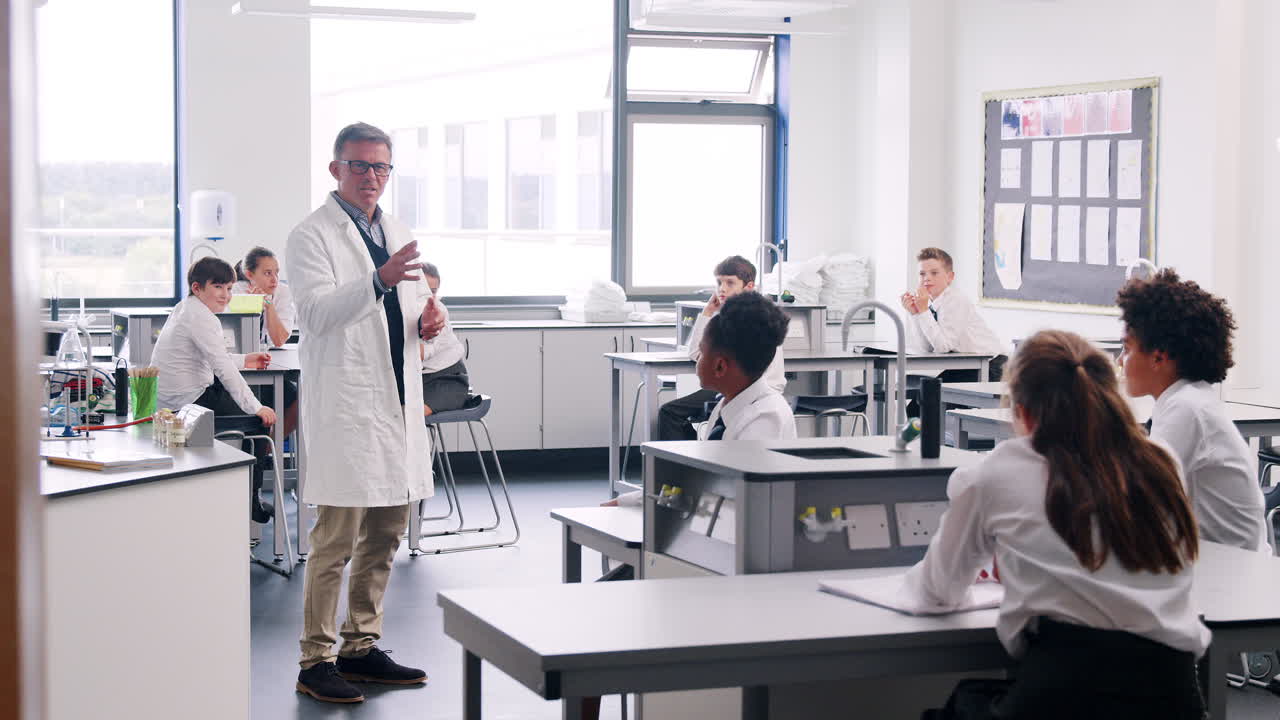 tutor de escuela secundaria masculino enseñando a estudiantes en uniforme sentados en bancos de trabajo en la clase de ciencias