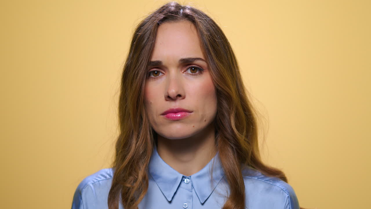 mujer seria sobre un fondo amarillo. mujer pensativa mirando a la cámara