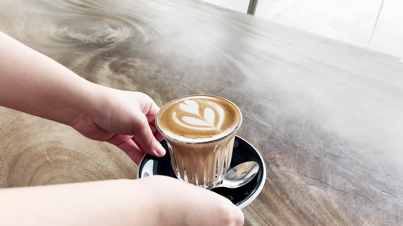 Glass of hot coffee latte is served to the table by great customer service staff member at the cafe, food and beverages hospitality industry