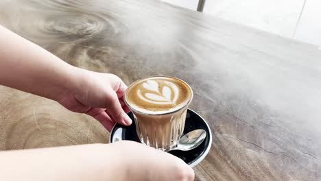 glass of hot coffee latte is served to the table by great customer service staff member at the cafe, food and beverages hospitality industry