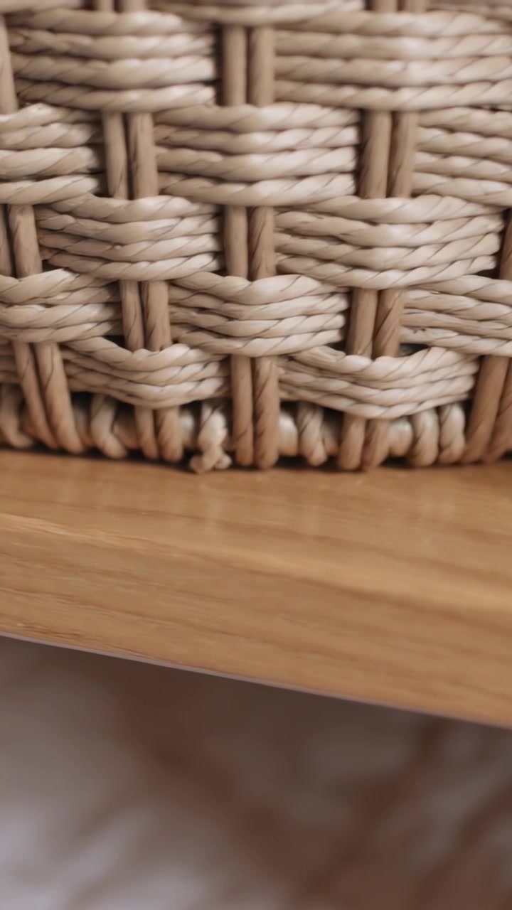 Video verticale: La telecamera si sposta verso l'alto, rivelando un cesto intrecciato su uno scaffale di legno chiaro e del tessuto.