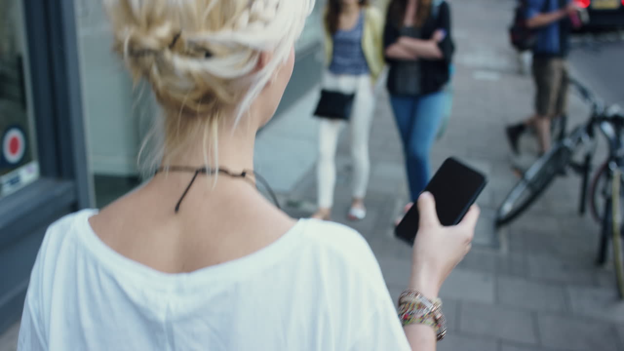 도시에서 스마트 폰을 사용하는 아름다운 금발