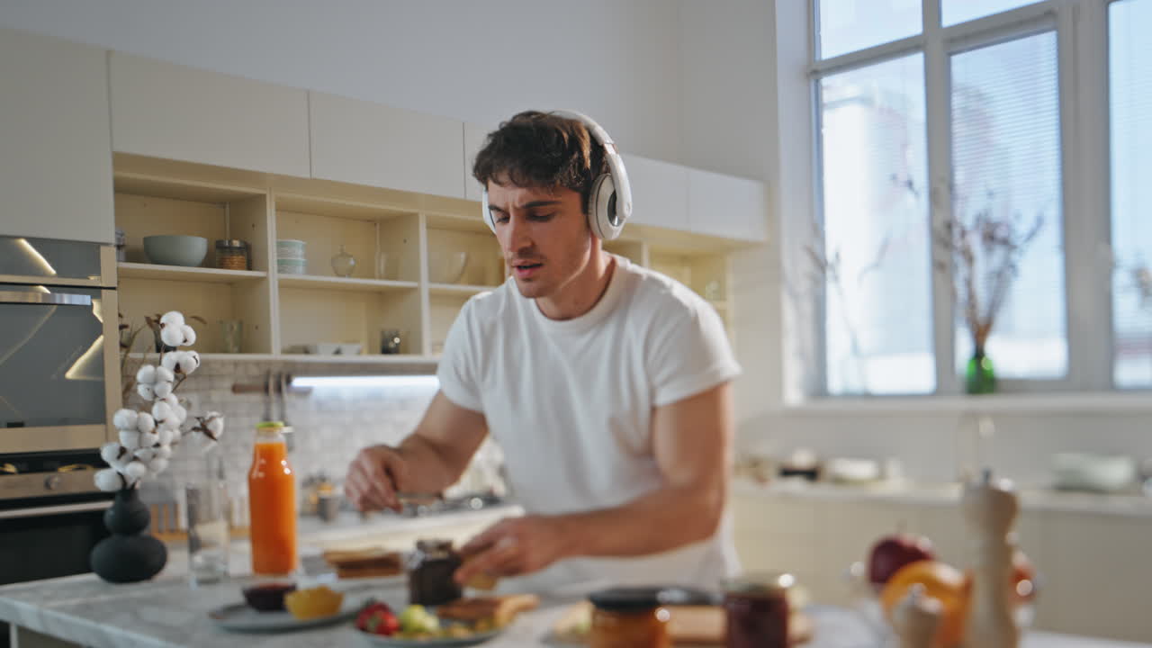 hombre escuchando música cocinando con auriculares en la cocina de cerca. hombre disfrutando de la canción