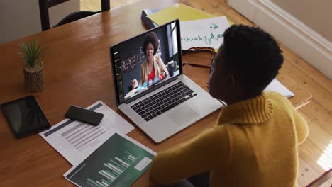 mujer afroamericana que usa una computadora portátil en una videollamada con una colega que trabaja desde casa