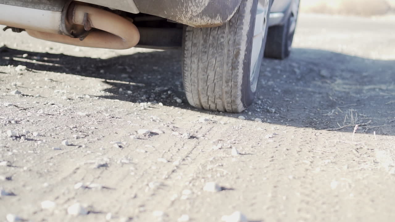 Low angle shot of a car moving forward on gravel