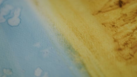 primer plano de pintura de oro arenoso azul acuoso y amarillo texturizado en lienzo